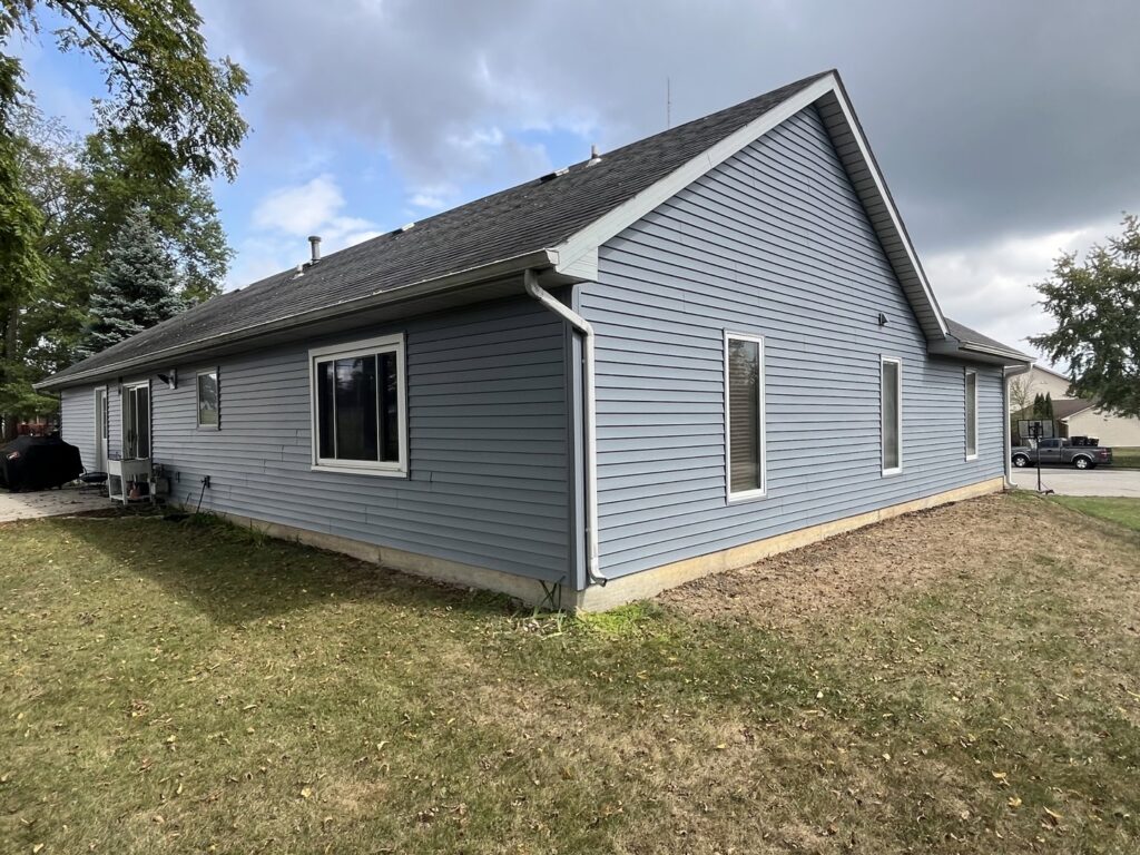 A side view of a house showcasing newly installed blue vinyl siding by Keep It Simple Construction LLC in Woodburn, IN.