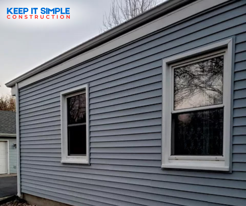 A side view of a house featuring new blue vinyl siding and white windows installed by Keep It Simple Construction LLC in Woodburn, IN.