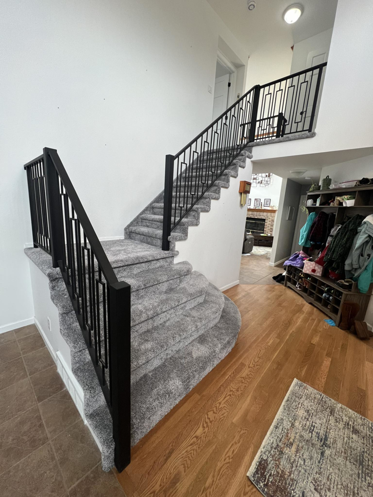 Newly installed carpet and black metal railings on a staircase by Elite Flooring Professionals in Pueblo, CO.