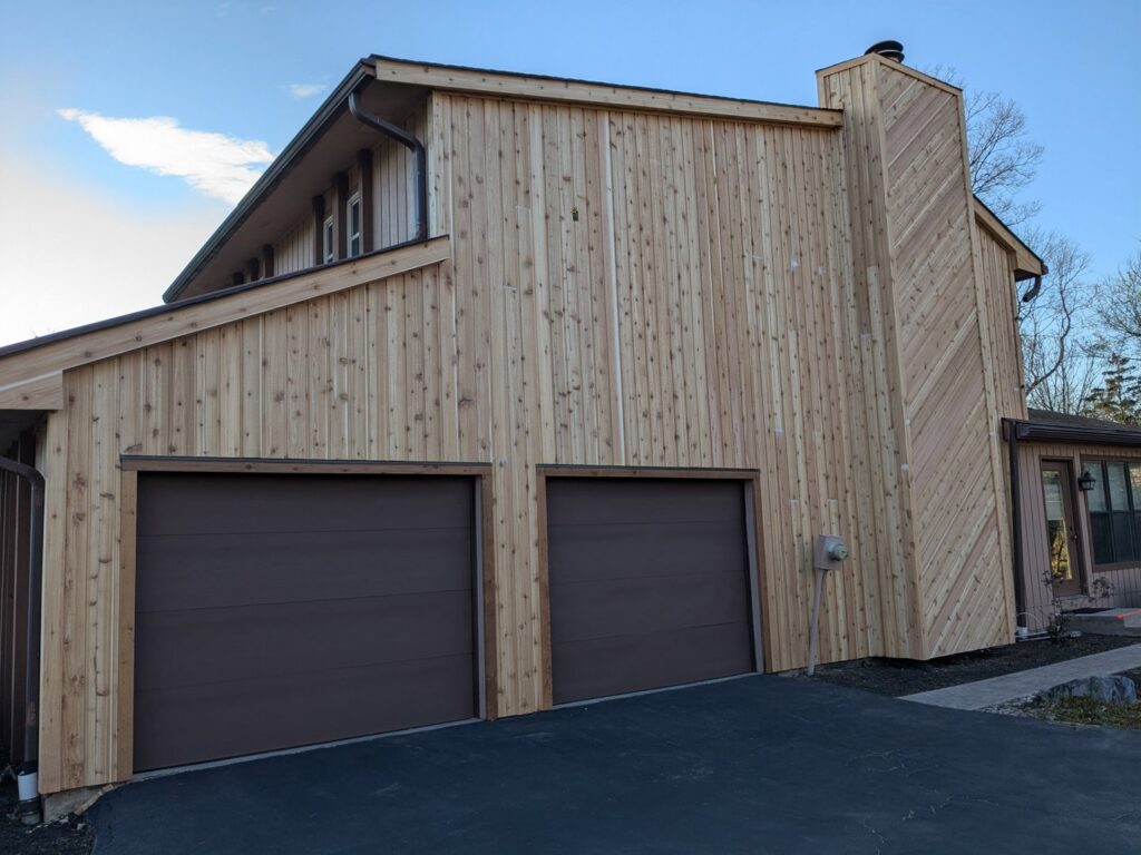 Newly installed cedar siding on a house with two garage doors by Cedar Siding Repair in Centerville, OH.