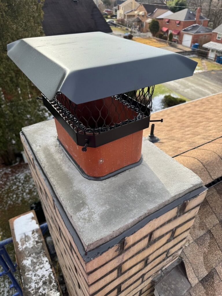 A newly installed metal cap on a brick chimney, showcasing masonry work by Prescott Roofing and Masonry in Carnegie, PA.