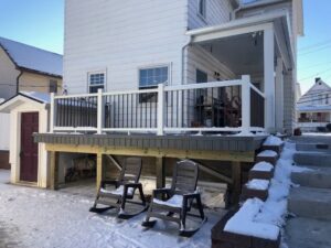 A newly constructed composite deck with black railings, lightly covered in snow, built by Gold-Mine Construction, LLC in Pittsburgh, PA.