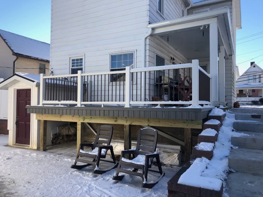 A newly constructed composite deck with black railings, lightly covered in snow, built by Gold-Mine Construction, LLC in Pittsburgh, PA.