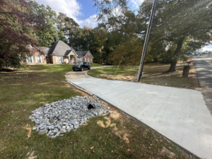 A newly installed concrete driveway with a gravel drainage system by Louisiana Land Solutions in West Monroe, LA.