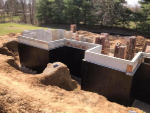 A newly constructed concrete foundation with black waterproofing applied by Complete Concrete of Indy, Inc. in Fishers, IN.