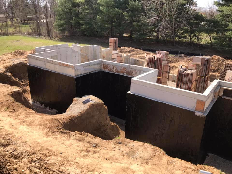 A newly constructed concrete foundation with black waterproofing applied by Complete Concrete of Indy, Inc. in Fishers, IN.