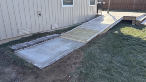 A newly installed concrete pad and wooden access ramp leading to a deck, completed by HW Handyman Services in Springfield, MO.