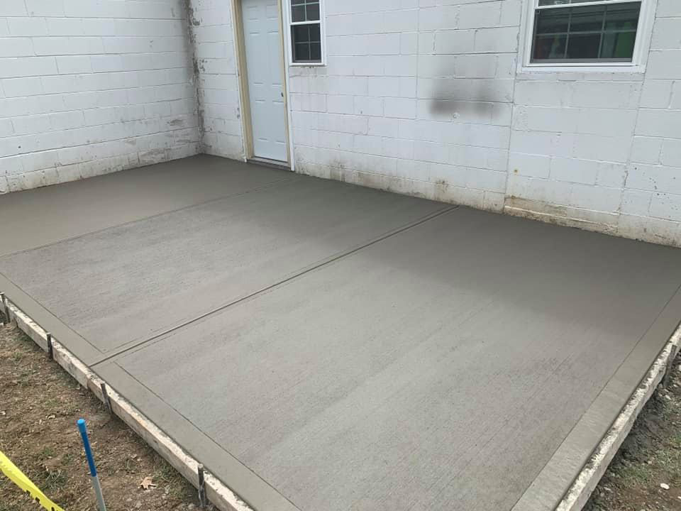 A newly installed concrete patio next to a building, expertly done by Complete Concrete of Indy, Inc. in Fishers, IN.