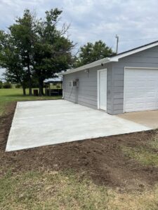 A newly poured concrete patio next to a garage by Smitty's Handyman Service LLC in Mesquite, TX.