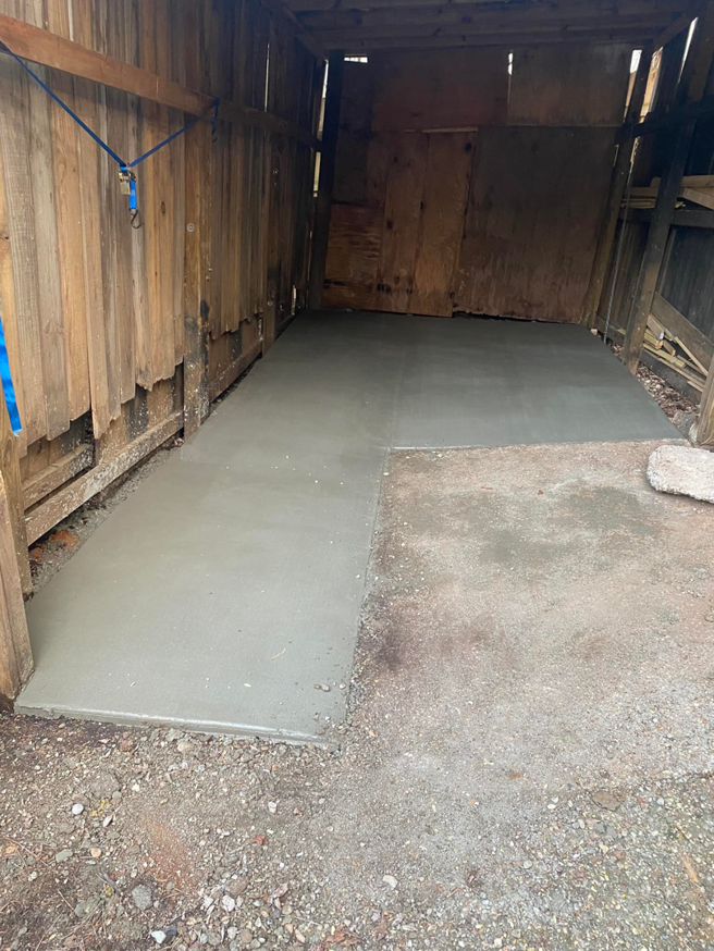 A newly poured concrete floor inside a wooden shed by B&H Homes in Shreveport, LA