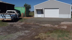 A newly poured concrete slab in front of a grey metal garage, completed by K&K Construction LLC in Enid, OK