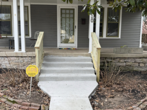 Newly installed concrete steps and wooden railings leading to a front door by Mr. GreenJeans in Indianapolis, IN.