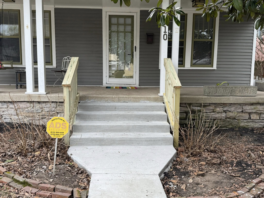 Newly installed concrete steps and wooden railings leading to a front door by Mr. GreenJeans in Indianapolis, IN.