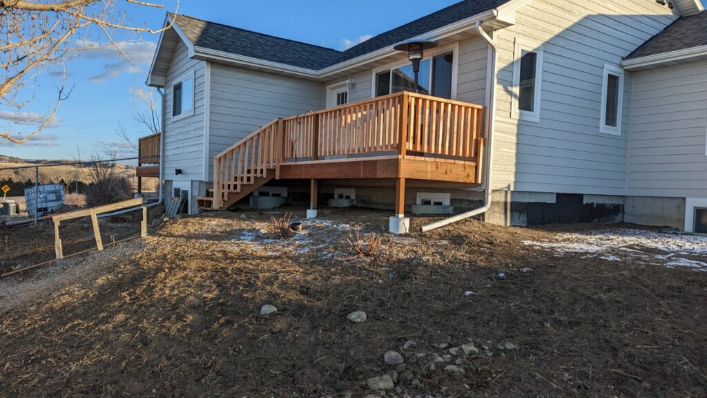 A newly constructed wooden deck attached to a house, built by Devil Dog Services LLC in Billings, MT.