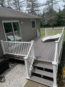 A newly constructed outdoor deck with white railings and stairs by Garbatini Contracting in Wallingford, CT.