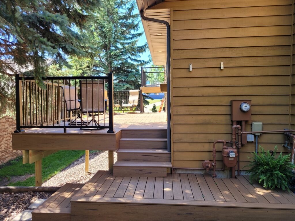 A newly constructed outdoor deck with stairs and black railing by Vander Wal Contracting, LLC in Bismarck, ND