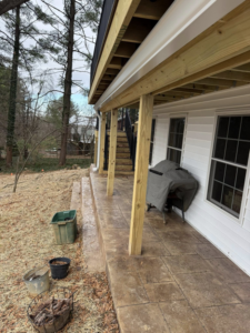 A newly constructed outdoor deck and patio area with fresh wood beams and white gutters by Rogers Remodeling in Bloomington, IN.