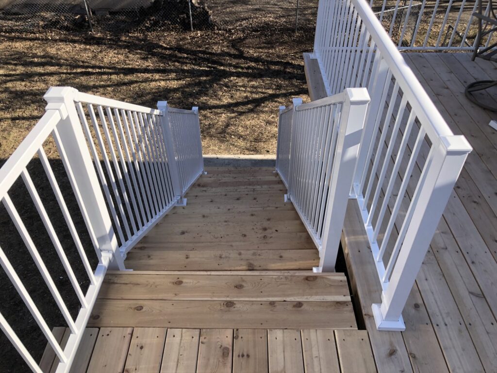 Newly installed wooden deck stairs with white railings by Nordic Construction in Plymouth, MN.