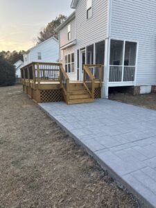 A newly constructed deck and stamped concrete patio at a residential property by Elite Xteriors NC in Cary, NC.