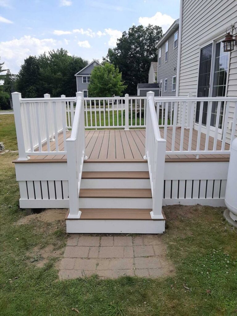 A newly constructed deck with steps and white railings, built by Sini's Handyman Services in Falmouth, ME.
