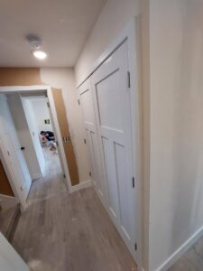 A hallway featuring newly installed white doors and trim, with walls prepped for finishing, by Jake and Jake Construction LLC in Sandy, UT.