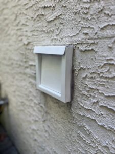 A clean, white dryer vent cover installed on the exterior wall of a house by Dryer Vent Cleaning of Delaware in Wilmington, DE.