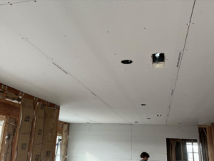 A newly installed drywall ceiling with recessed light cutouts and wall insulation by Kliesen Construction Company in Pueblo, CO.