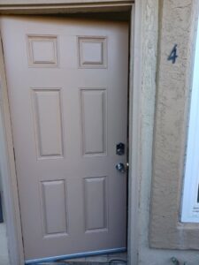 A newly installed beige entry door with a modern lock, showcasing door replacement services by Integrity Management in San Diego, CA.