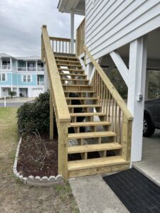 A newly built exterior wooden staircase providing access to a raised home by Seaside Craftworks LLC in Wilmington, NC.