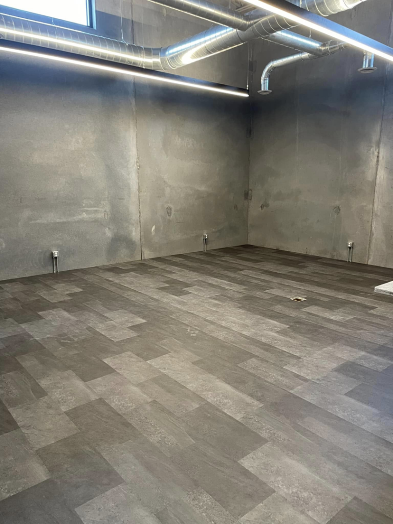 Newly installed flooring and exposed ductwork in a renovated room by DeJean Home Renovation in Yankton, SD.