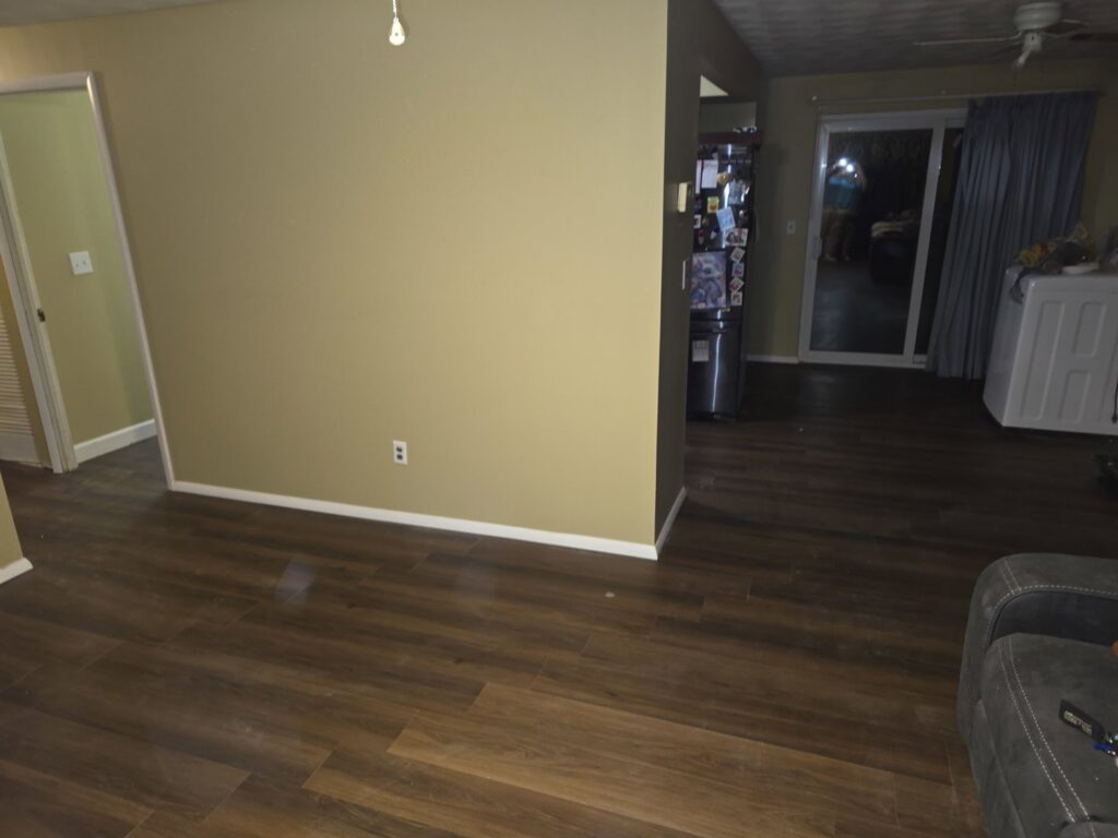 A living area with newly installed flooring and freshly painted walls by D-N-M Construction & Property Maintanence LLC in Dayton, OH.