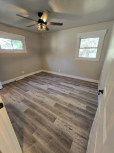 An empty room showcasing new laminate flooring, fresh paint, and a ceiling fan installation by Next Level Finish in Fort Collins, CO.