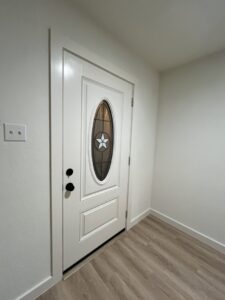 A newly installed white front door with decorative glass by San Marcos Drywall and Paint in Austin, TX