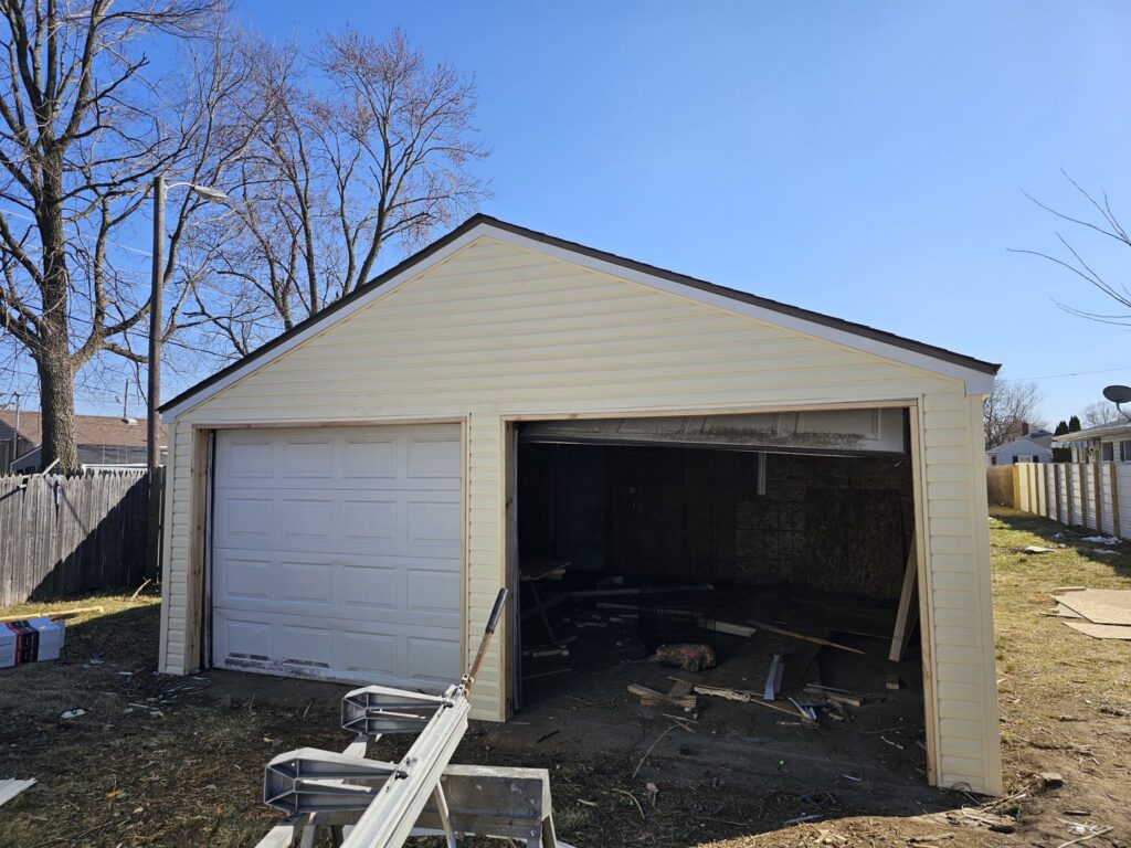Newly installed siding and garage door on a detached garage by Urban Restoration, LLC in Indianapolis, IN