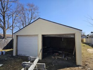 Newly installed siding and garage door on a detached garage by Urban Restoration, LLC in Indianapolis, IN