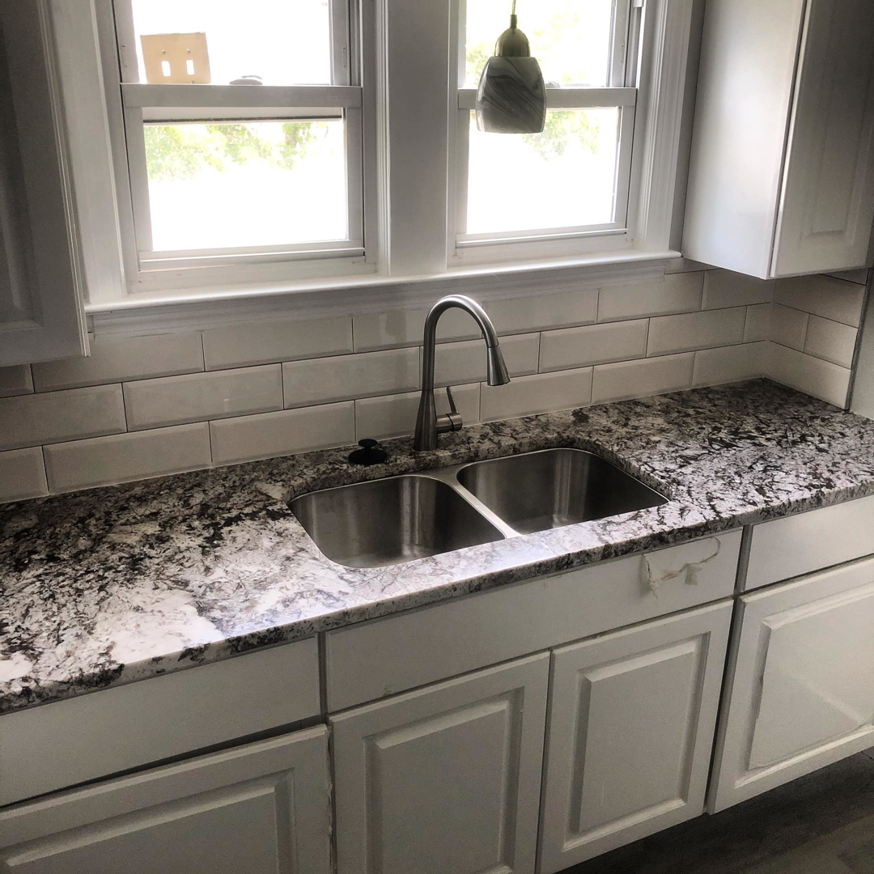 A newly installed granite kitchen countertop with a double sink and subway tile backsplash by Fine Design Marble And Granite in Springfield, MA.