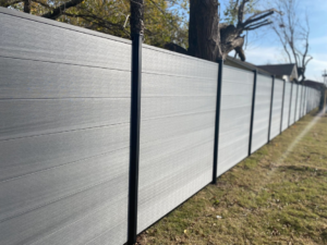 A long, newly installed grey composite fence by A/M Fence, providing handyman services in Norman, OK