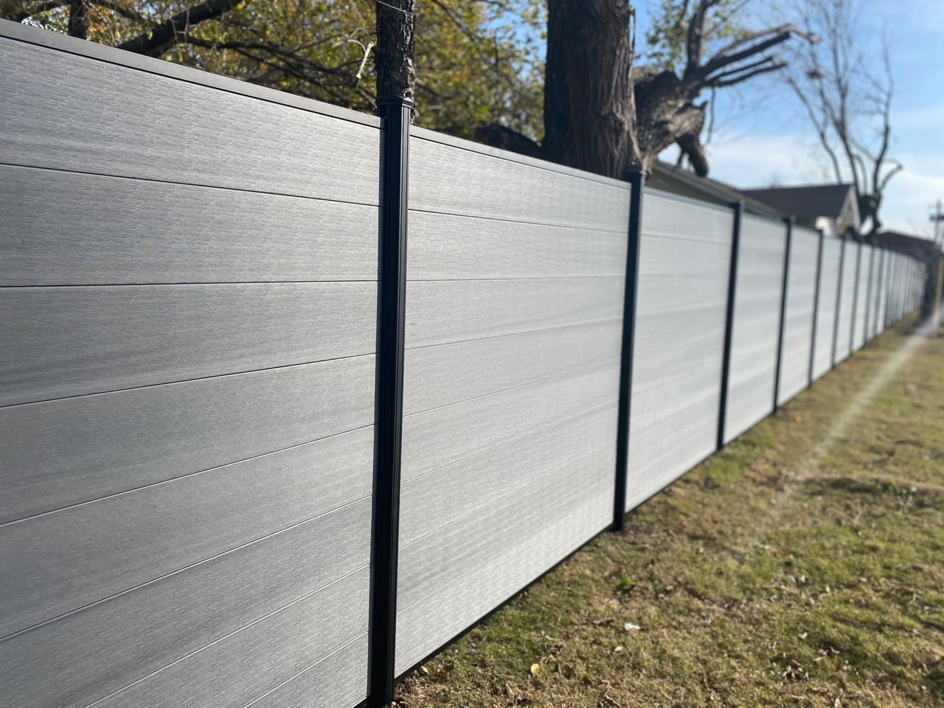 A long, newly installed grey composite fence by A/M Fence, providing handyman services in Norman, OK