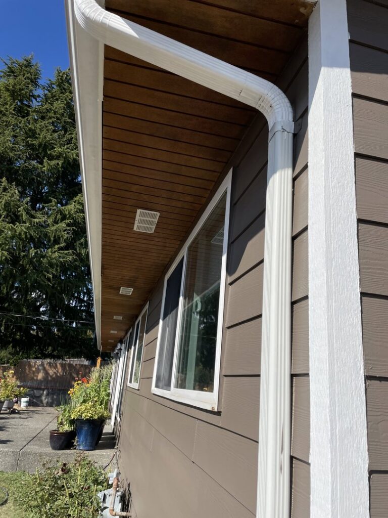 Newly installed white gutters and updated siding on the exterior of a house by Guzmanremodeling LlC in Renton, WA.