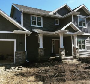 Recently installed gutters and downspouts on a house, with disturbed ground from construction by Gutter Flow7 LLC in Madison, WI.