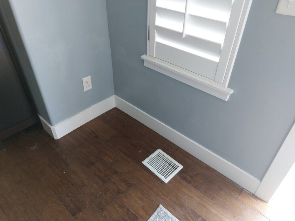 A room showcasing newly installed hardwood flooring and white baseboards, a service by Jake and Jake Construction LLC in Sandy, UT.