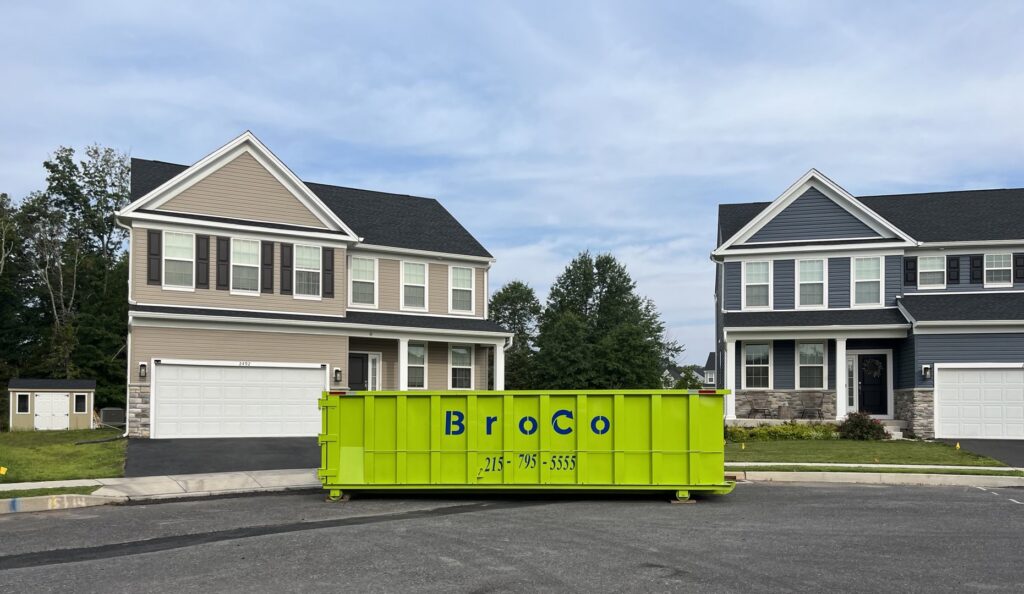 A green Broco Waste & Recycling dumpster at a new home construction site in Warminster, PA.