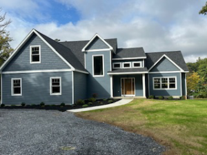A newly constructed blue home with mixed siding and a light wood front door by McDonald Custom Homes in Schenectady, NY.