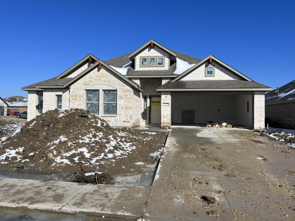 Exterior view of a new home construction project with a pile of dirt in front by Trident General Contracting in Plano, TX.