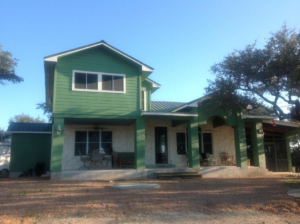 Exterior view of a newly constructed home with green siding and stone by Valdez Remodeling & Weatherization Inc. in Austin, TX