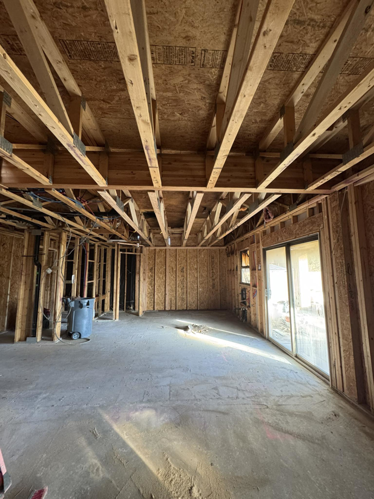 Interior view of new home construction showing exposed wooden framing and concrete floor by CK Customs LLC in Surprise, AZ.
