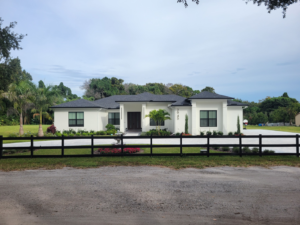 A newly built modern white home with a black fence, showcasing new construction by Williams Custom Construction in Orlando, FL.