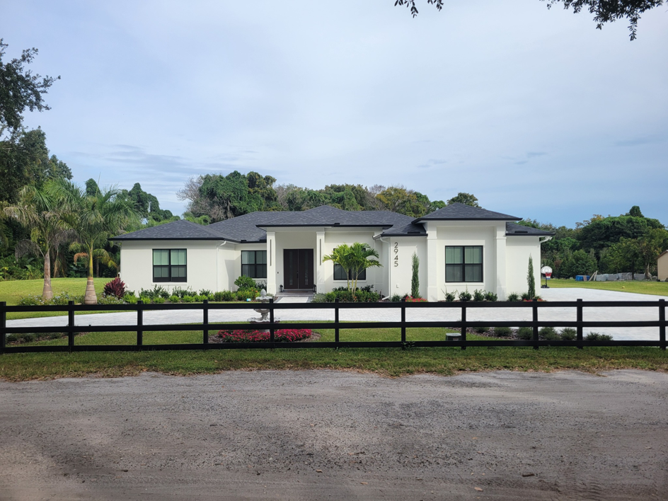 A newly built modern white home with a black fence, showcasing new construction by Williams Custom Construction in Orlando, FL.