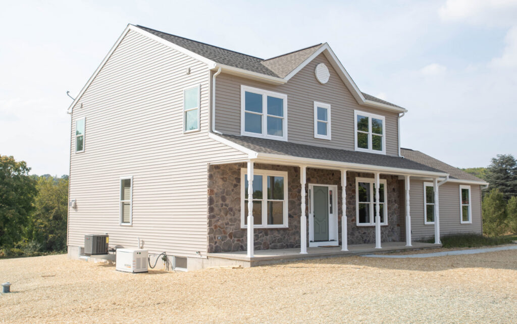 Exterior of a newly constructed home with light siding and stone accents by Corrado Custom Homes, Inc. in Kutztown, PA