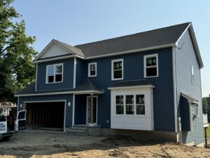 The exterior of a newly constructed home with blue siding and white windows, showcasing a large home improvement project by Home pro handyman llc in Olathe, KS